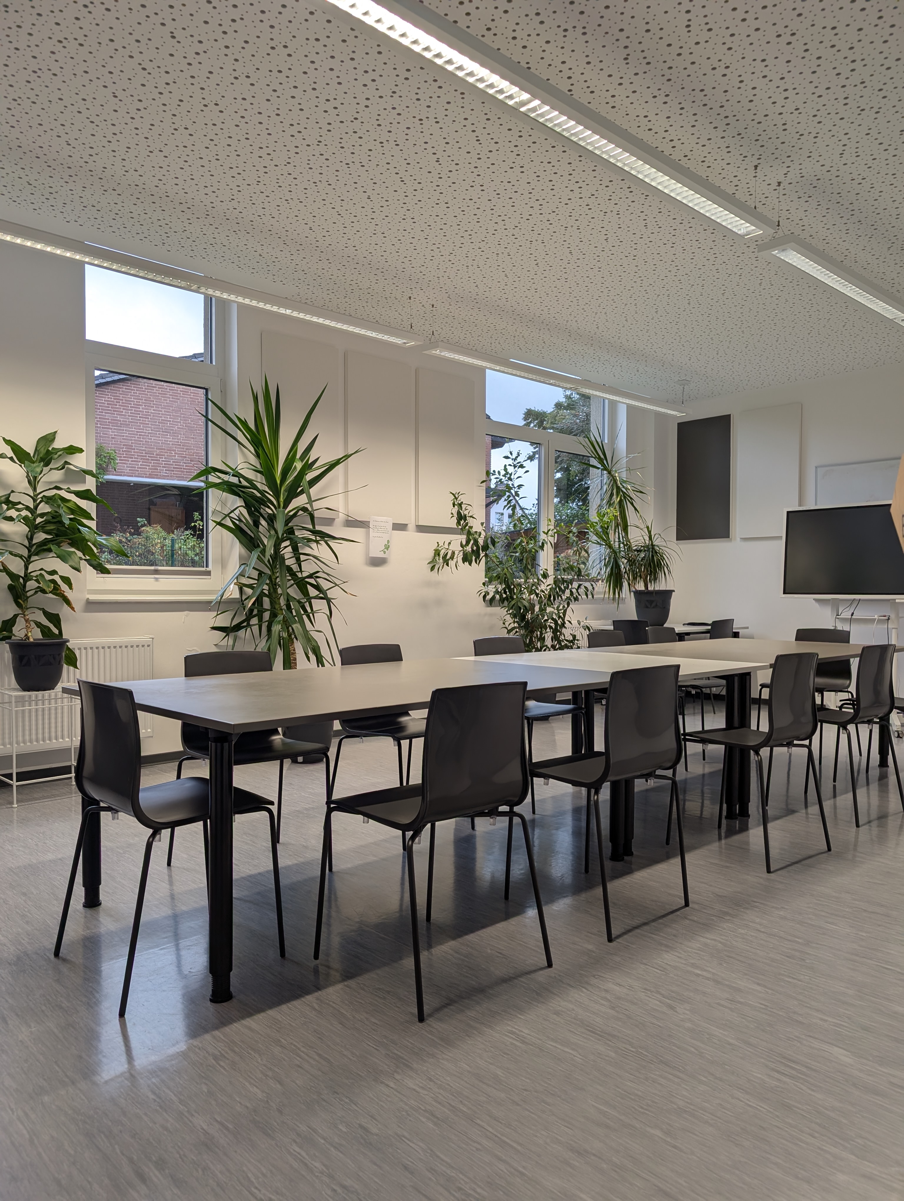 Essbereich mit Tischen, Stühlen und Smartboard